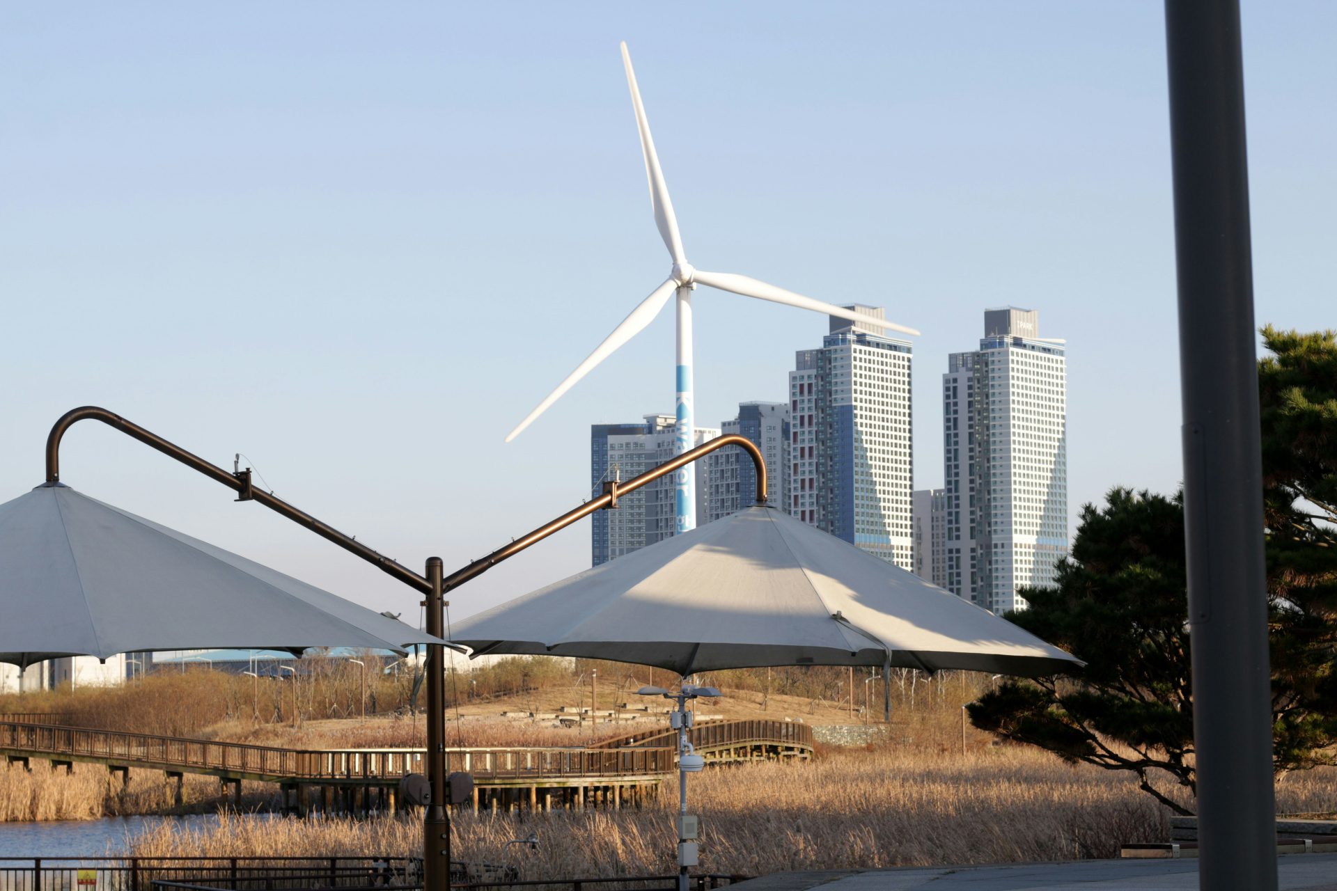 Aerogenerador y edificios modernos junto al agua.